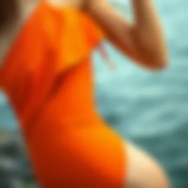 Close-up of the unique design details of an orange one shoulder swimsuit