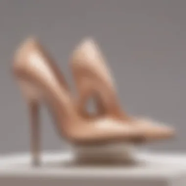 An elegant pair of nude patent leather pumps displayed on a minimalist pedestal